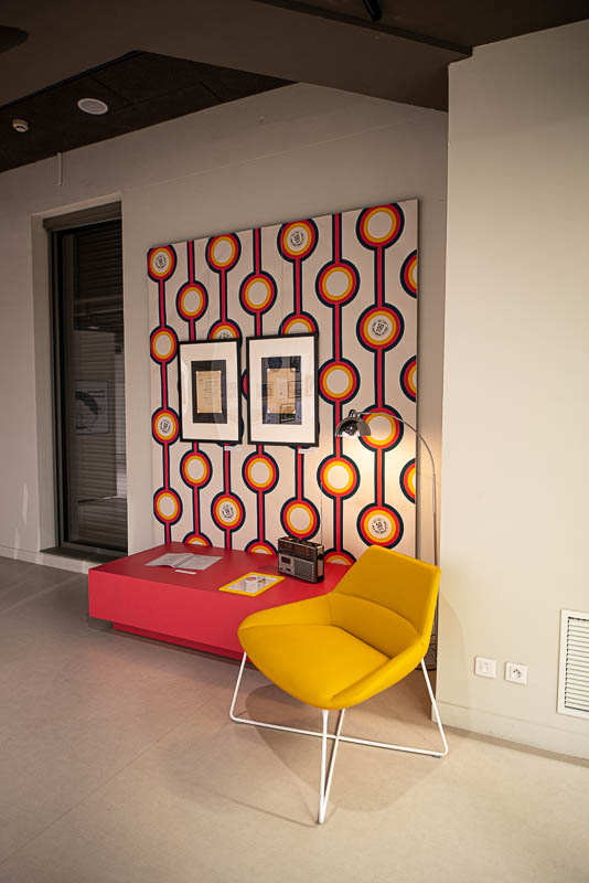 décor d'introduction inspiré des années 70 fauteuil jaune, socle orangé et papier peint