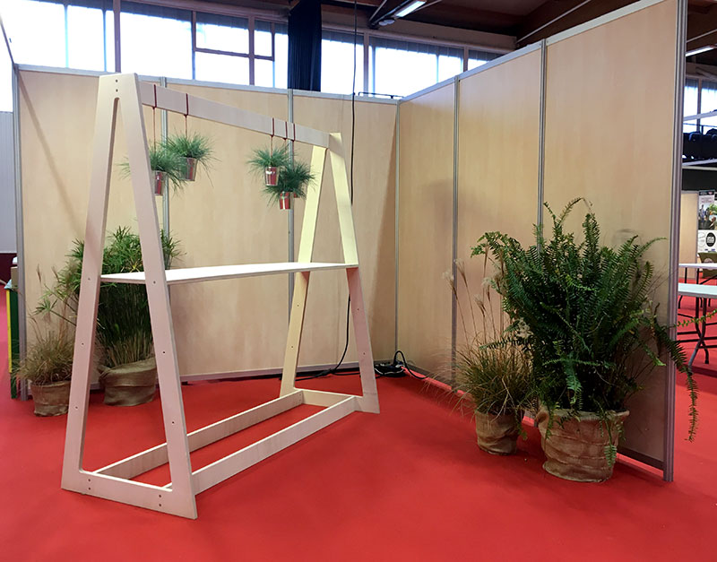 Corner de stand avec un mange debout design en bois garni de plantes vertes